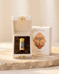 Sacrasoul Myrrh Essential Oil — the bottle in its cream velvet presentation case beside the branded gift box, warm directional light