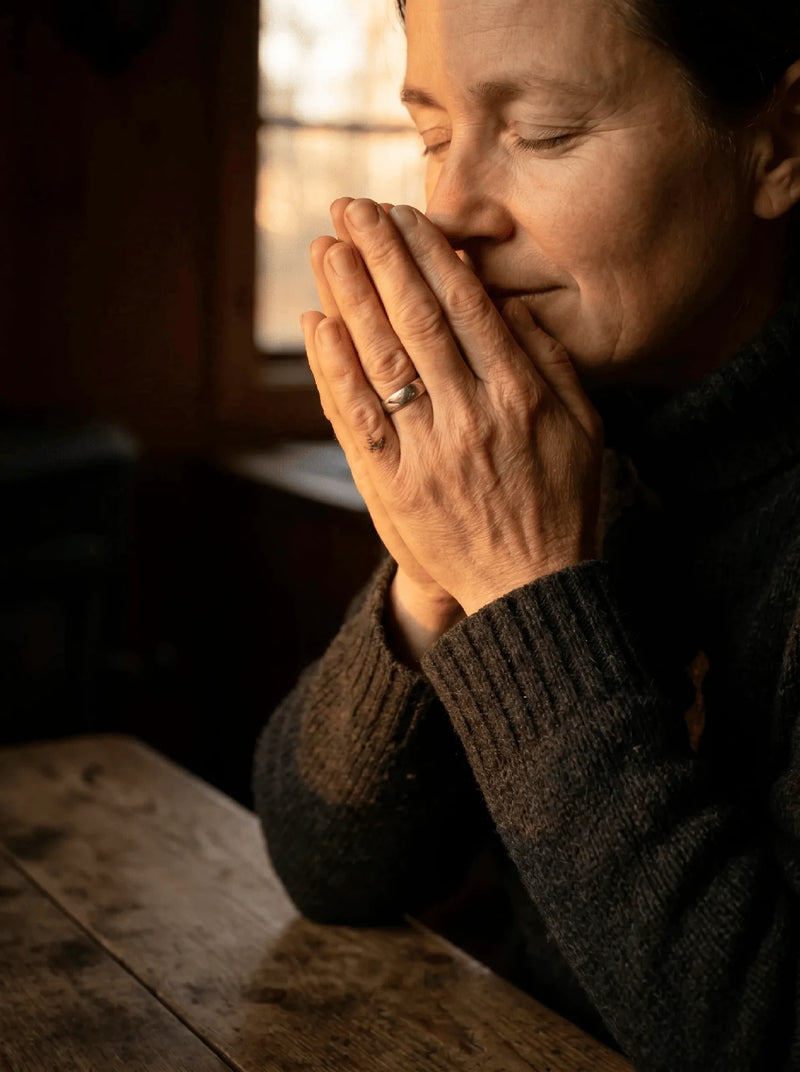 A woman inhaling deeply from her cupped palms, warm amber light, the inhale ritual