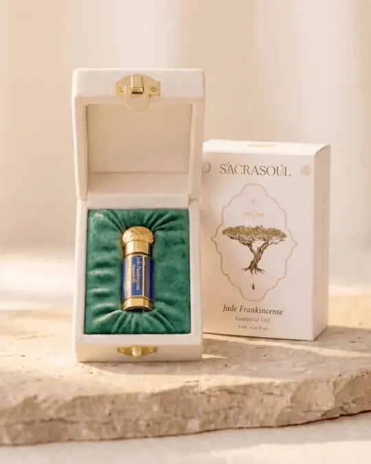 The gold and blue Jade Frankincense essential oil bottle in its open cream velvet case, beside the printed carton reading Sacrasoul, Jade Frankincense Essential Oil, 6 ml.